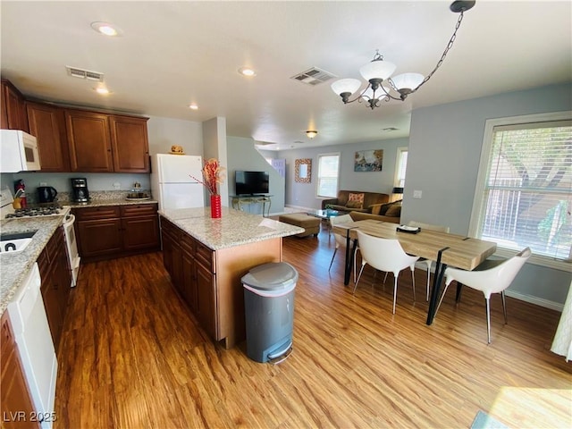 11117 Okeefe Ct, Las Vegas, NV 89144 - kitchen featuring white appliances, wood finished floors, open floor plan, a kitchen island, and a chandelier