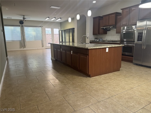 7934 Cape Flattery Ave, Las Vegas, NV 89147 - kitchen featuring stainless steel appliances, under cabinet range hood, a center island with sink, ceiling fan, and light stone countertops