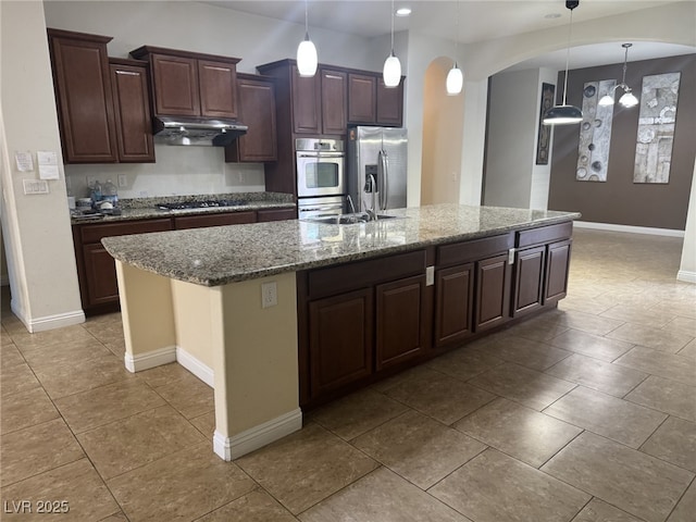 7934 Cape Flattery Ave, Las Vegas, NV 89147 - kitchen with stainless steel appliances, a sink, under cabinet range hood, baseboards, and a large island with sink