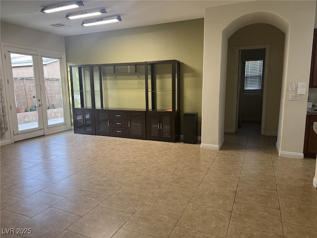 7934 Cape Flattery Ave, Las Vegas, NV 89147 - tiled empty room featuring french doors, arched walkways, and baseboards