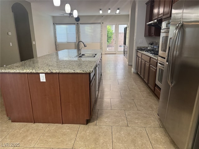 7934 Cape Flattery Ave, Las Vegas, NV 89147 - kitchen with stainless steel appliances, a sink, an island with sink, light stone counters, and light tile patterned flooring