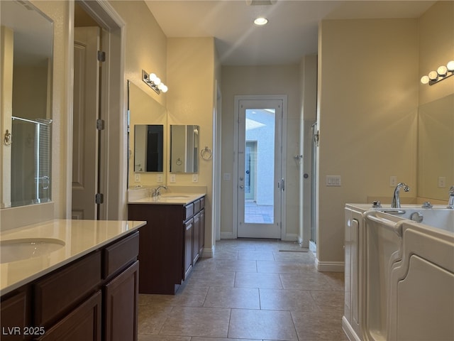 7934 Cape Flattery Ave, Las Vegas, NV 89147 - bathroom featuring washing machine and dryer, a stall shower, baseboards, two vanities, and recessed lighting