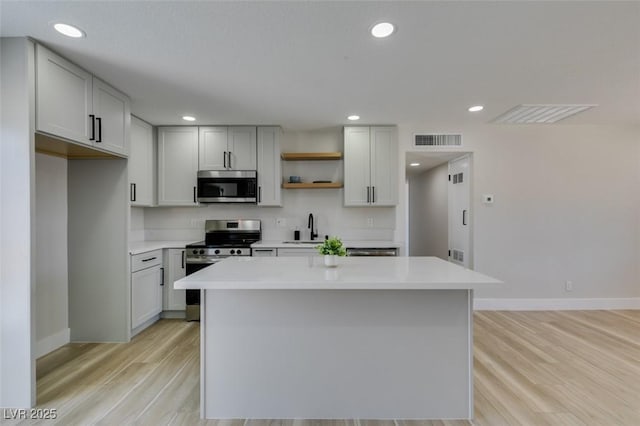 6100 Fawn Cir, Las Vegas, NV 89107 - kitchen with appliances with stainless steel finishes, a sink, baseboards, open shelves, and light wood-style floors
