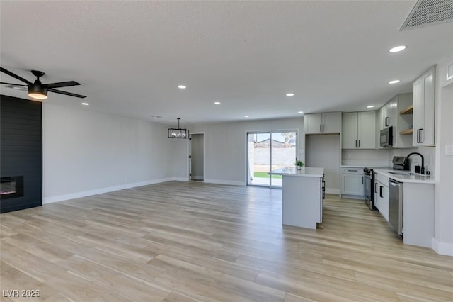 6100 Fawn Cir, Las Vegas, NV 89107 - kitchen featuring appliances with stainless steel finishes, a ceiling fan, open floor plan, a center island, and light countertops
