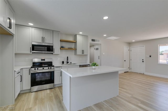 6100 Fawn Cir, Las Vegas, NV 89107 - kitchen with appliances with stainless steel finishes, a sink, open shelves, light wood finished floors, and light countertops