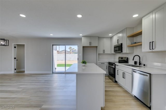 6100 Fawn Cir, Las Vegas, NV 89107 - kitchen with appliances with stainless steel finishes, a sink, open shelves, a kitchen island, and light wood finished floors