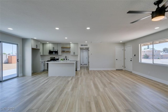 6100 Fawn Cir, Las Vegas, NV 89107 - kitchen with stainless steel microwave, open shelves, light wood-style flooring, gray cabinetry, and open floor plan