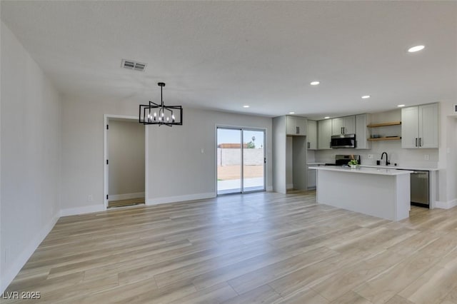 6100 Fawn Cir, Las Vegas, NV 89107 - kitchen featuring appliances with stainless steel finishes, open shelves, light wood-style floors, a chandelier, and baseboards