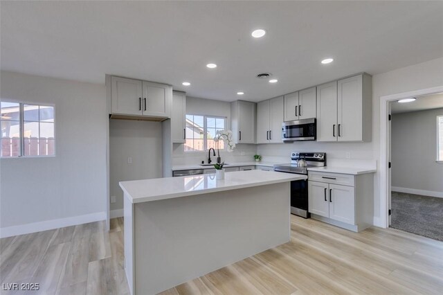 4360 El Tovar Rd, Las Vegas, NV 89115 - kitchen with appliances with stainless steel finishes, a kitchen island, light countertops, light wood-style floors, and recessed lighting