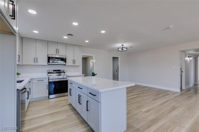 4360 El Tovar Rd, Las Vegas, NV 89115 - kitchen with stainless steel appliances, light countertops, a kitchen island, light wood-type flooring, and recessed lighting