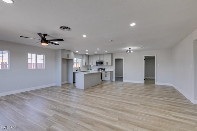 4360 El Tovar Rd, Las Vegas, NV 89115 - unfurnished living room featuring baseboards, recessed lighting, light wood-type flooring, a ceiling fan, and a sink