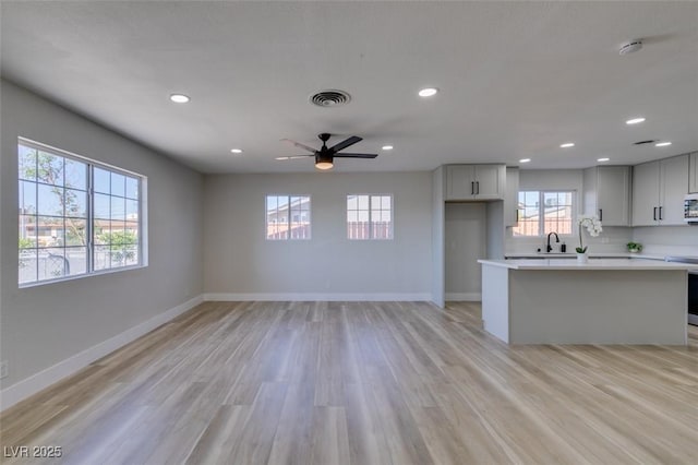 4360 El Tovar Rd, Las Vegas, NV 89115 - unfurnished living room with light wood-type flooring, ceiling fan, recessed lighting, baseboards, and a sink