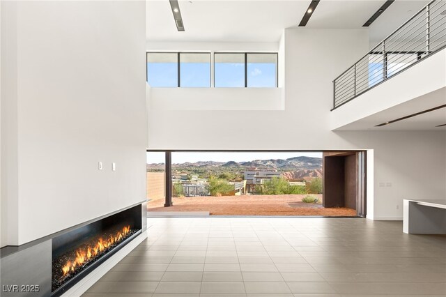 25 Canyon Bay Dr, Henderson, NV 89011 - unfurnished living room featuring a high ceiling and a warm lit fireplace
