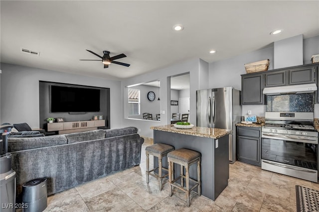 10952 Napa Ridge Dr, Las Vegas, NV 89144 - kitchen featuring stainless steel appliances, under cabinet range hood, a ceiling fan, a kitchen bar, and a kitchen island