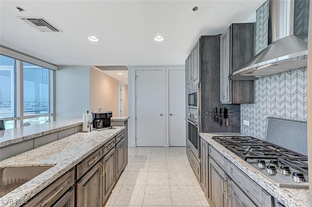 4525 Dean Martin Dr Unit 1208, Las Vegas, NV 89103 - kitchen with wall chimney exhaust hood, appliances with stainless steel finishes, tasteful backsplash, light stone countertops, and recessed lighting