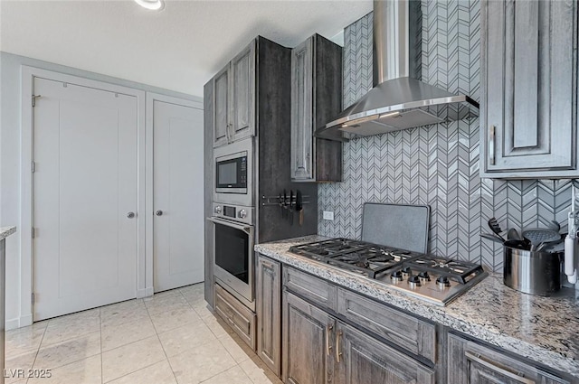 4525 Dean Martin Dr Unit 1208, Las Vegas, NV 89103 - kitchen featuring wall chimney exhaust hood, appliances with stainless steel finishes, backsplash, light tile patterned floors, and light stone counters
