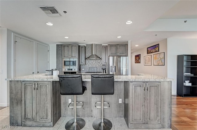 4525 Dean Martin Dr Unit 1208, Las Vegas, NV 89103 - kitchen featuring appliances with stainless steel finishes, wall chimney range hood, gray cabinetry, recessed lighting, and light stone counters