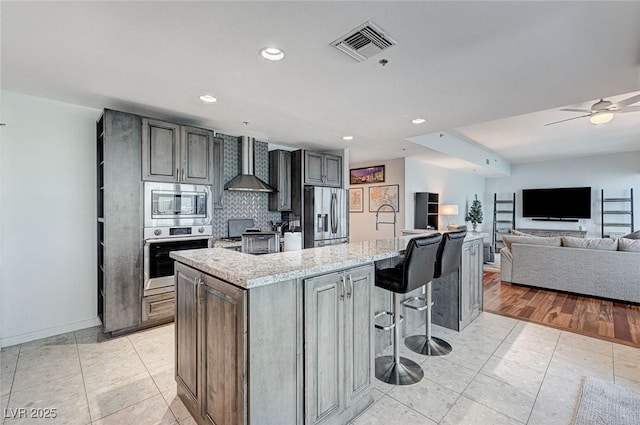 4525 Dean Martin Dr Unit 1208, Las Vegas, NV 89103 - kitchen featuring appliances with stainless steel finishes, wall chimney exhaust hood, light stone countertops, decorative backsplash, and light tile patterned floors