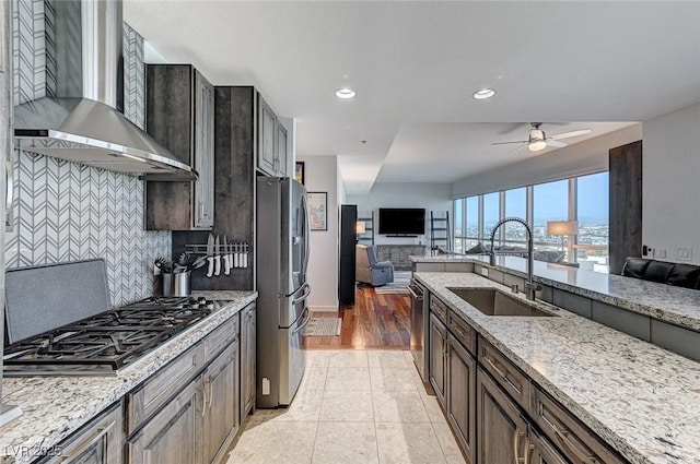 4525 Dean Martin Dr Unit 1208, Las Vegas, NV 89103 - kitchen with wall chimney exhaust hood, appliances with stainless steel finishes, open floor plan, light stone countertops, and backsplash