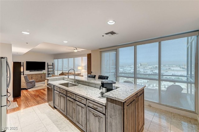 4525 Dean Martin Dr Unit 1208, Las Vegas, NV 89103 - kitchen featuring stainless steel appliances, open floor plan, a kitchen island with sink, light stone counters, and light tile patterned floors