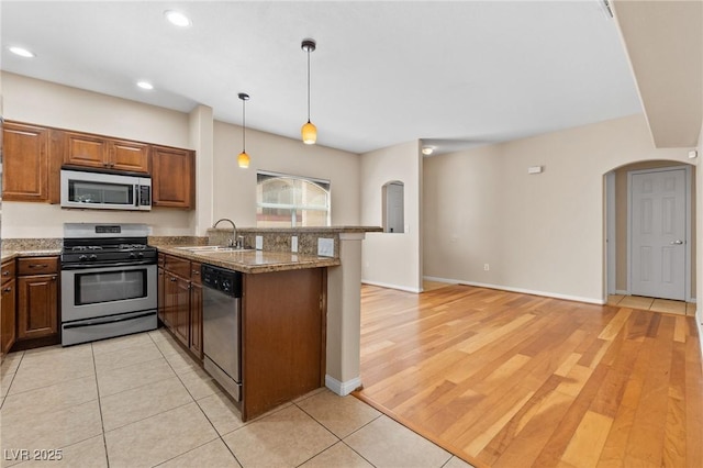 8409 Running Deer Ave Unit 203, Las Vegas, NV 89145 - kitchen featuring appliances with stainless steel finishes, a peninsula, arched walkways, decorative light fixtures, and recessed lighting