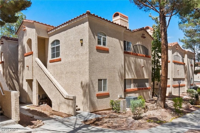 8409 Running Deer Ave Unit 203, Las Vegas, NV 89145 - view of home's exterior featuring stucco siding, a chimney, and a tiled roof