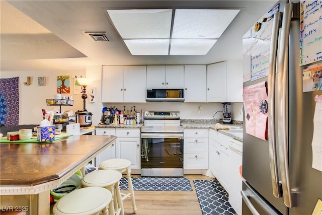 5706 W Lake Mead Blvd, Las Vegas, NV 89108 - kitchen featuring appliances with stainless steel finishes, light wood-style floors, and white cabinetry