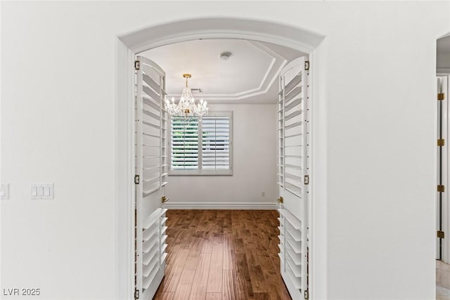 2846 Barrow Downs St, Las Vegas, NV 89135 - walk in closet featuring a chandelier, wood finished floors, arched walkways, and a raised ceiling