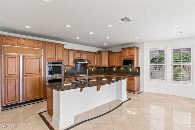 2846 Barrow Downs St, Las Vegas, NV 89135 - kitchen featuring stainless steel appliances, under cabinet range hood, a sink, decorative backsplash, and dark stone counters