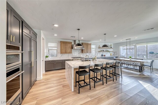 365 Crown Mesa Ave, Las Vegas, NV 89138 - kitchen featuring extractor fan, light wood-style floors, recessed lighting, healthy amount of natural light, and light stone counters