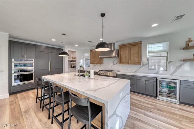 365 Crown Mesa Ave, Las Vegas, NV 89138 - kitchen with wine cooler, light stone counters, wall chimney exhaust hood, light wood finished floors, and tasteful backsplash