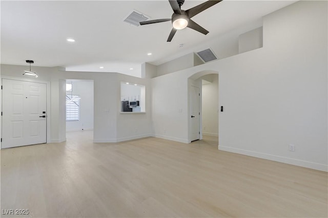 7865 March Brown Ave, Las Vegas, NV 89149 - unfurnished living room featuring a ceiling fan, light wood finished floors, lofted ceiling, arched walkways, and baseboards