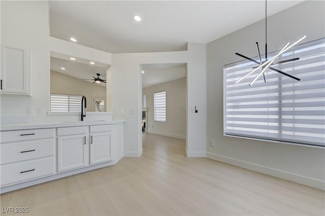 7865 March Brown Ave, Las Vegas, NV 89149 - kitchen with a sink, light wood-style floors, light countertops, white cabinetry, and a chandelier