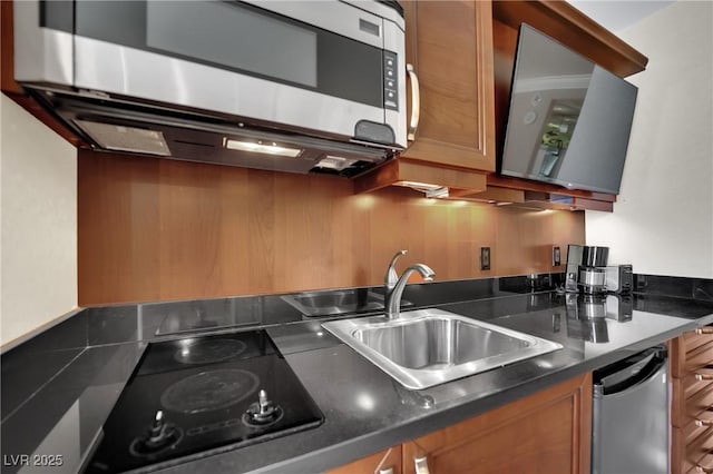 135 E Harmon Ave Unit 315, Las Vegas, NV 89109 - kitchen with appliances with stainless steel finishes, a sink, dark countertops, brown cabinetry, and backsplash