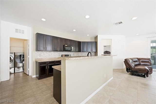 9104 Ashiwi Ave, Las Vegas, NV 89178 - kitchen with black microwave, separate washer and dryer, decorative backsplash, baseboards, and recessed lighting