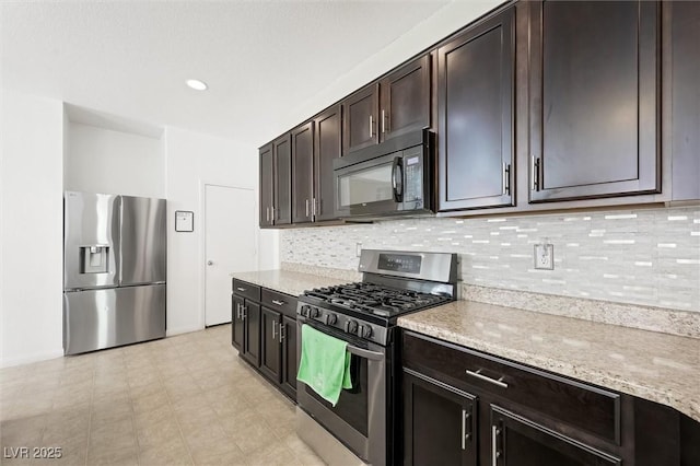 9104 Ashiwi Ave, Las Vegas, NV 89178 - kitchen featuring stainless steel appliances, decorative backsplash, dark brown cabinets, and light stone counters