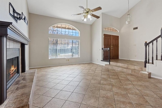 2812 Via Avanti St, Henderson, NV 89074 - unfurnished living room featuring high vaulted ceiling, stairs, a lit fireplace, ceiling fan, and light tile patterned floors