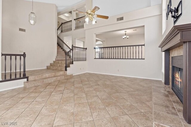 2812 Via Avanti St, Henderson, NV 89074 - unfurnished living room featuring stairway, a glass covered fireplace, a high ceiling, ceiling fan, and baseboards
