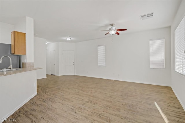 9535 Stills Way, Las Vegas, NV 89148 - unfurnished living room with a ceiling fan, light wood finished floors, a sink, and baseboards
