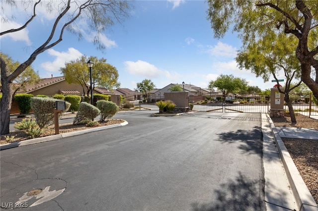 9393 New Utrecht St, Las Vegas, NV 89178 - view of asphalt road with a gate, curbs, a residential view, street lights, and a gated entry
