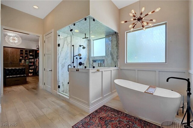 2111 Bogart Ct, Las Vegas, NV 89117 - bathroom with a chandelier, a shower stall, a freestanding bath, wood finished floors, and a decorative wall