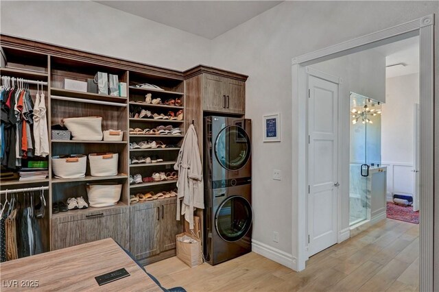 2111 Bogart Ct, Las Vegas, NV 89117 - washroom with stacked washer and clothes dryer, light wood finished floors, a chandelier, cabinet space, and baseboards
