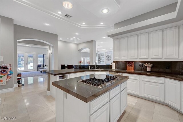 2111 Bogart Ct, Las Vegas, NV 89117 - kitchen featuring arched walkways, stainless steel gas cooktop, dark countertops, backsplash, and a peninsula
