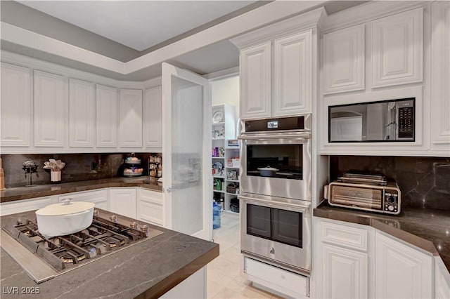 2111 Bogart Ct, Las Vegas, NV 89117 - kitchen with appliances with stainless steel finishes, dark countertops, white cabinetry, and decorative backsplash