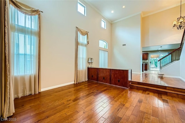 3412 Crystal Tower St, Las Vegas, NV 89129 - unfurnished living room featuring hardwood / wood-style floors, ornamental molding, baseboards, stairs, and a towering ceiling