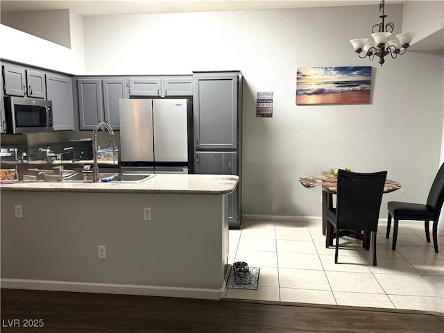 1367 Sun Pillars Ave, Henderson, NV 89014 - kitchen with appliances with stainless steel finishes, gray cabinetry, a chandelier, a sink, and baseboards