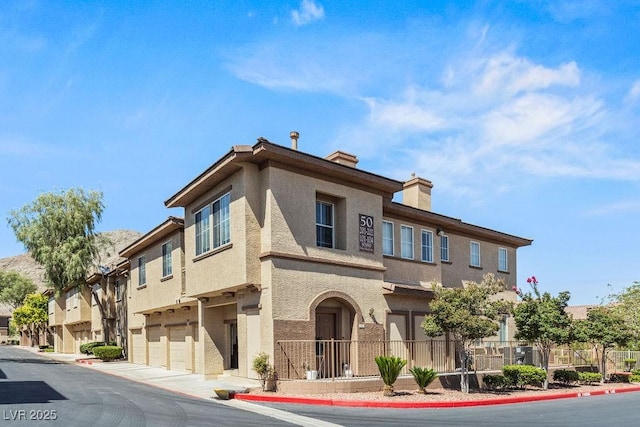 10180 Delray Beach Ave Unit 202, Las Vegas, NV 89129 - view of front of house with stucco siding, a garage, a residential view, and a chimney