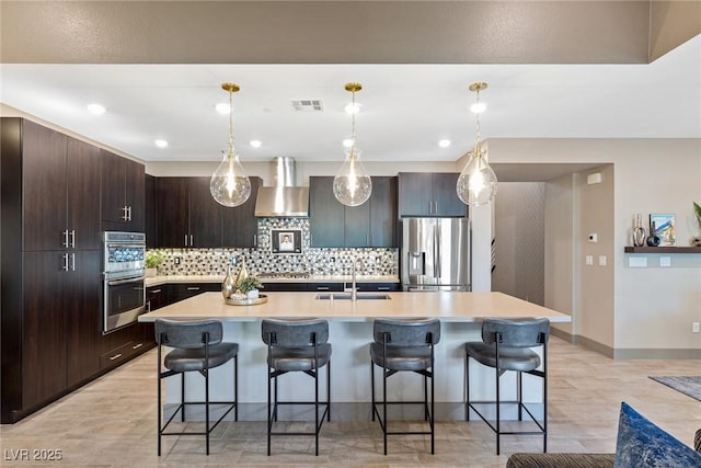 4290 Solace St, Las Vegas, NV 89135 - kitchen featuring stainless steel appliances, wall chimney exhaust hood, a sink, tasteful backsplash, and a kitchen bar