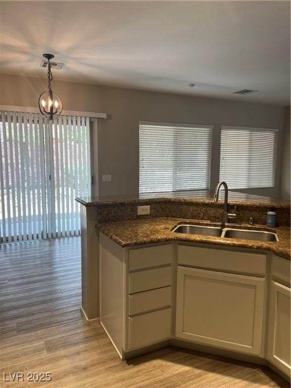 6092 Fox Creek Ave, Las Vegas, NV 89122 - kitchen featuring a sink, light wood-style floors, dark stone countertops, and hanging light fixtures