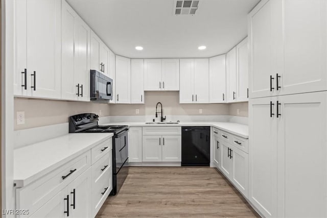 4805 Jay Ave, Las Vegas, NV 89130 - kitchen with black appliances, a sink, recessed lighting, white cabinets, and light wood-style flooring